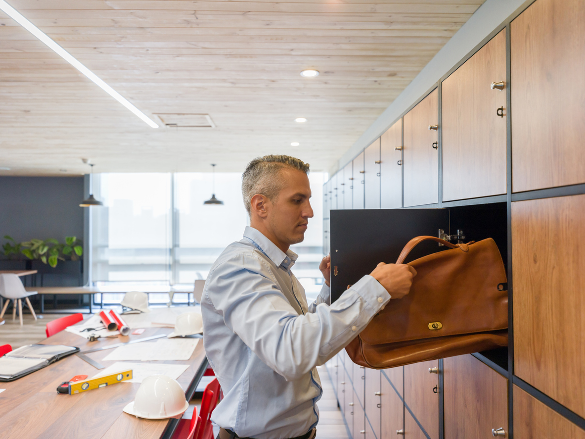 Portrait of a Latin American business man at a co-working space putting his briefcase in a locker