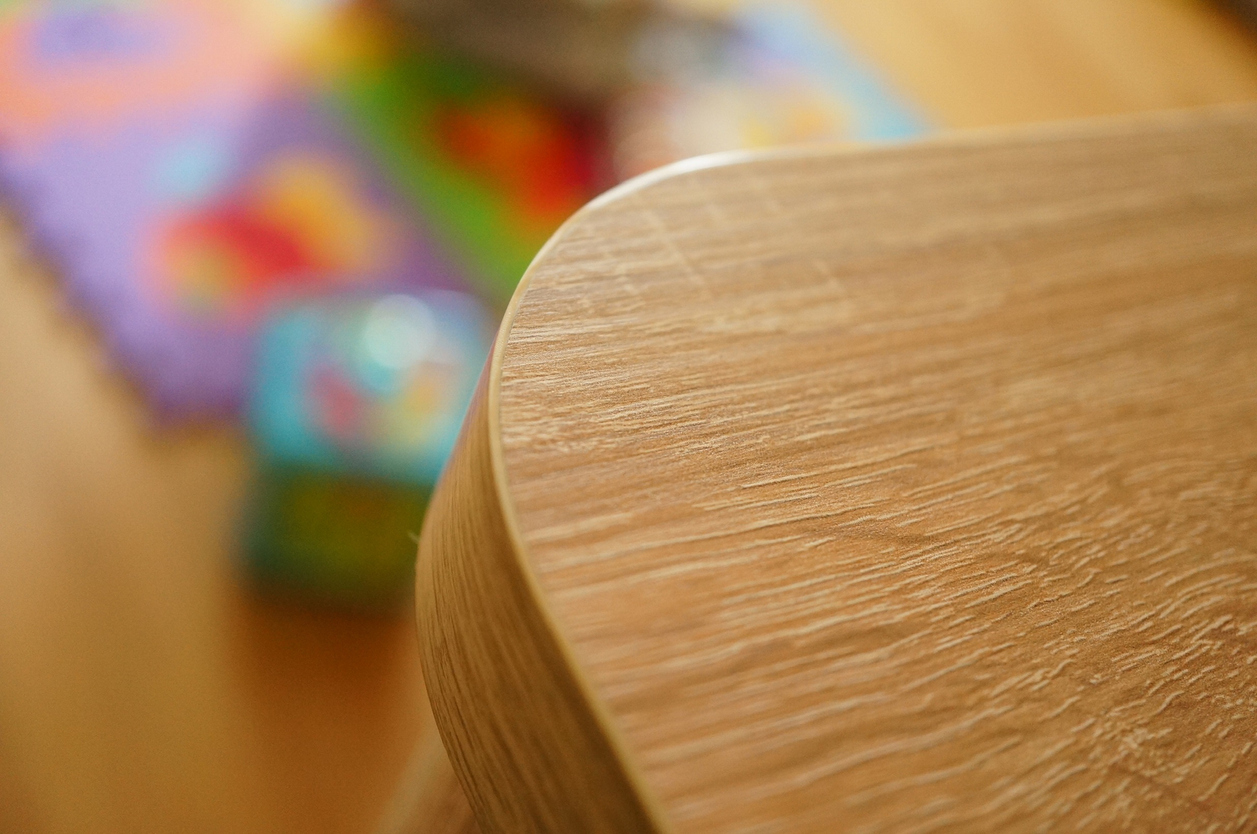 A closeup shot of a curved edge of a wooden table with a blurred background